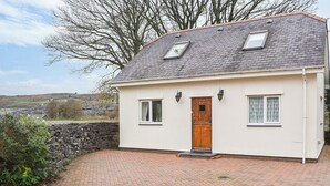 A single-story house with a stone wall, a wooden door, and two windows. - 1 bedroom accommodation in Windermere (Windermere)