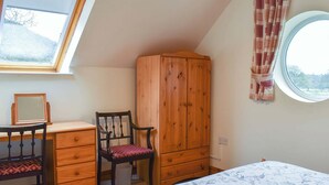 A bedroom with a bed, a wooden wardrobe, a desk with a chair, a window, and a view of trees. - 1 bedroom accommodation in Windermere (Windermere)