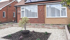 Una casa residencial con paneles solares en el techo, fachada de ladrillo y jardín con una planta en maceta.