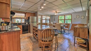 A spacious kitchen with wooden cabinets, a central island, and a dining area with a table and chairs. - Charming Pymatuning Lake House Near Park & Beach (Andover)