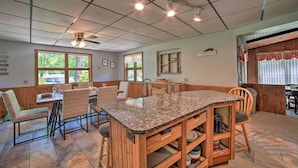 A kitchen with a granite countertop, wooden cabinets, and a dining area with chairs and a table. - Charming Pymatuning Lake House Near Park & Beach (Andover)