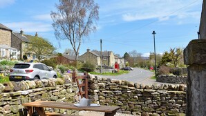 A stone wall with a picnic table, a silver car parked nearby, and a clear blue sky.