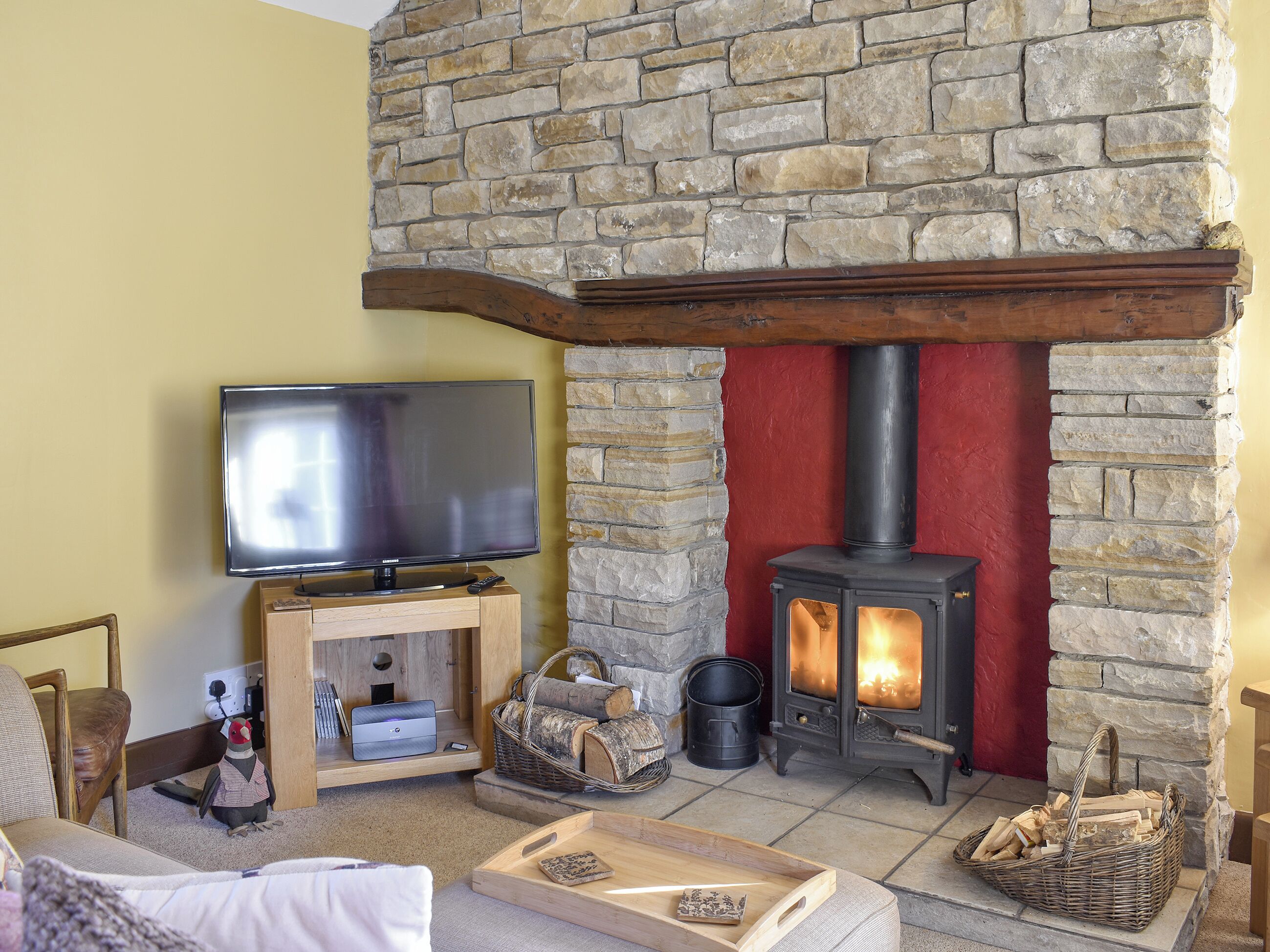 A cozy living room with a stone fireplace, a television, and a comfortable seating area.