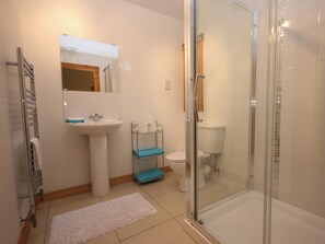 Ein Badezimmer mit Duschkabine aus Glas, Waschbecken, Toilette und Handtuchhalter.