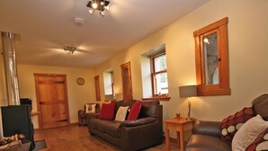 Ein Wohnzimmer mit Kamin, Holzboden, einer Couch, einem Couchtisch und einer Lampe.