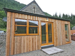 A wooden cabin with a stone roof, large windows, and a gravel driveway. - A beautiful barn conversion set within the grounds of a working farm. (Benmore near Dunoon)
