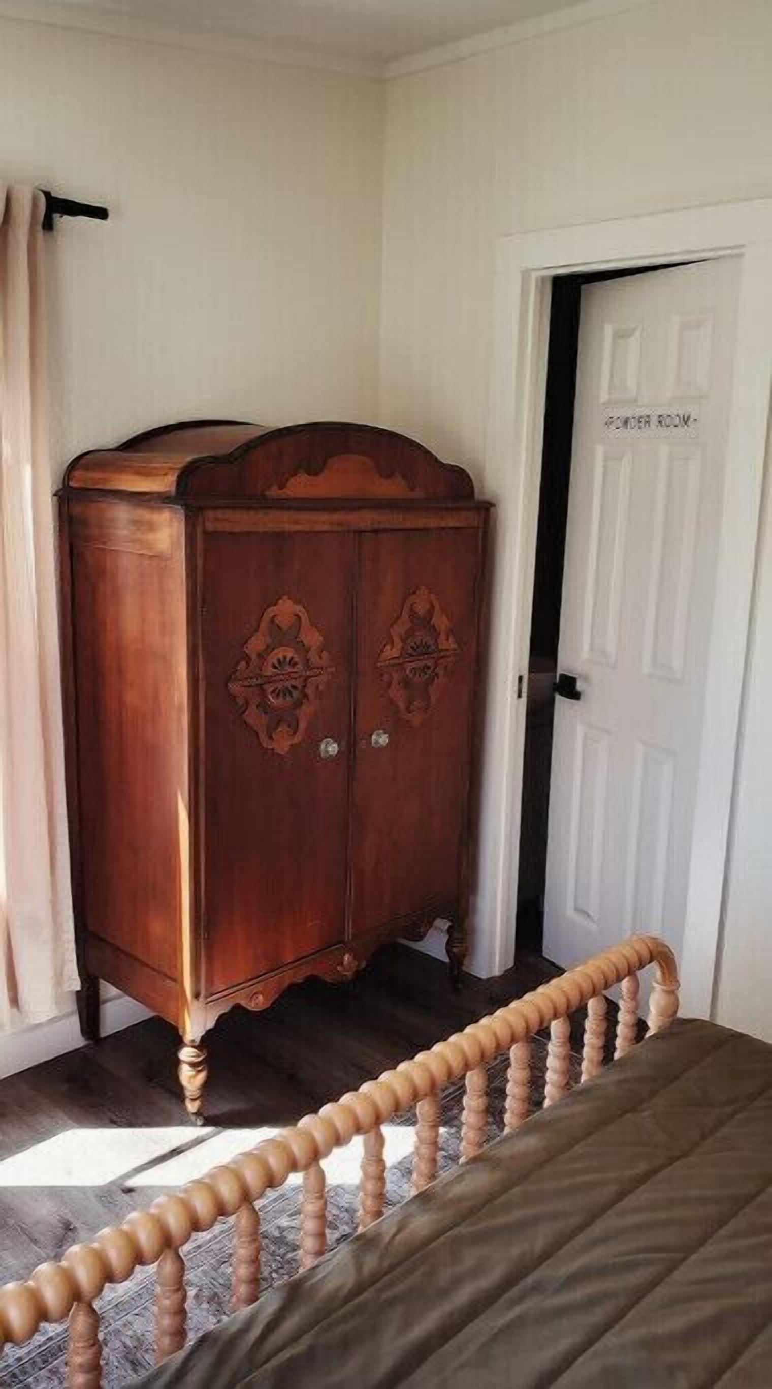 Ein Schlafzimmer mit einem Holfachschrank, einem Bett und einer Tür mit der Aufschrift 'Powder Room'.