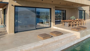 Ein modernes, zweistöckiges Haus mit Swimmingpool, großen Glasfenstern und einer Terrassenanlage.