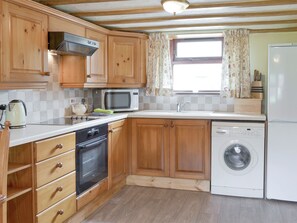A compact kitchen with wooden cabinets, a microwave, a dishwasher, and a washing machine.
