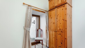 A room with a wooden wardrobe, a chair, and a window with curtains. - 2 bedroom accommodation in Mey, near Thurso (Mey, near Thurso)