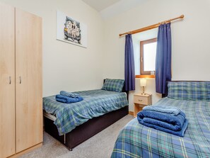 A bedroom with two beds, a wardrobe, a painting, a window with curtains, and a bedside table with a lamp. - 2 bedroom accommodation in Mey, near Thurso (Mey, near Thurso)