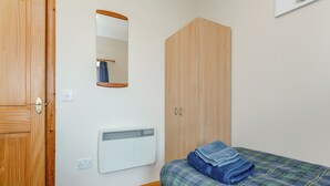 A bedroom with a wooden door, a mirror, a wardrobe, a radiator, and a bed with a plaid duvet. - 2 bedroom accommodation in Mey, near Thurso (Mey, near Thurso)
