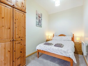 A bedroom with a wooden bed, two bedside tables with lamps, a radiator, and a wardrobe. - 2 bedroom accommodation in Mey, near Thurso (Mey, near Thurso)