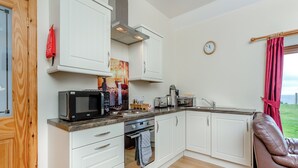 A compact kitchen with white cabinetry, a microwave, a toaster, and a sink. - 2 bedroom accommodation in Mey, near Thurso (Mey, near Thurso)
