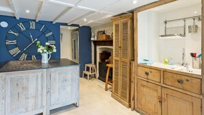 A kitchen with a large wall clock, wooden cabinets, and a marble countertop. - 3 bedroom accommodation in 11 Above Town (11 Above Town)