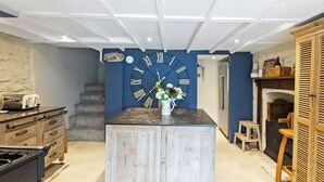 A kitchen with a large clock, wooden cabinets, a stove, and a staircase leading to another level. - 3 bedroom accommodation in 11 Above Town (11 Above Town)