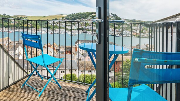 A balcony with blue chairs and a table overlooking a marina with boats and buildings. - 3 bedroom accommodation in 11 Above Town (11 Above Town)