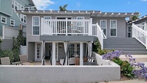Une maison à deux étages dotée d’un balcon, d’une terrasse couverte et d’un escalier menant à l’étage supérieur.