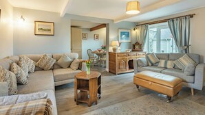 A living room with two sofas, a wooden side table, a coffee table, a lamp, and a clock on a dresser. - 3 bedroom accommodation in Llanfwrog, near Holyhead (Llanfwrog, near Holyhead)