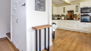Una cocina moderna con armarios blancos, un banco de madera y un cuadro de un tren en la pared.