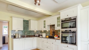 Una cocina moderna con armarios blancos, un salpicadero verde y dos hornos empotrados.