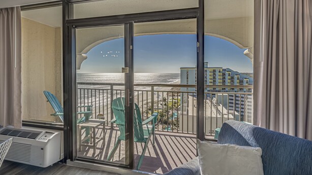 A balcony with a view of the beach and ocean, featuring a sofa and chairs. - Beautiful Ocean Views, on 15th floor! (Myrtle Beach)