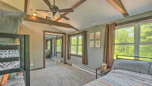 A bedroom with bunk beds, a ceiling fan, large windows with curtains, and a view of greenery outside. - Relax & Renew in Serene Mountain Cottage (Albrightsville)