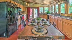 A spacious kitchen with a large island, wooden cabinets, and a stone wall. - Relax & Renew in Serene Mountain Cottage (Albrightsville)