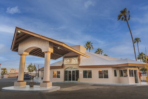 Hotel El Camino med reception, palmer og en overdækket indgang.