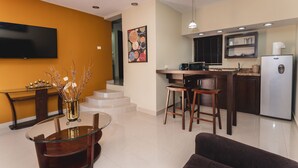 A modern kitchen with a refrigerator, microwave, and stove. There is a dining area with a glass table and chairs.