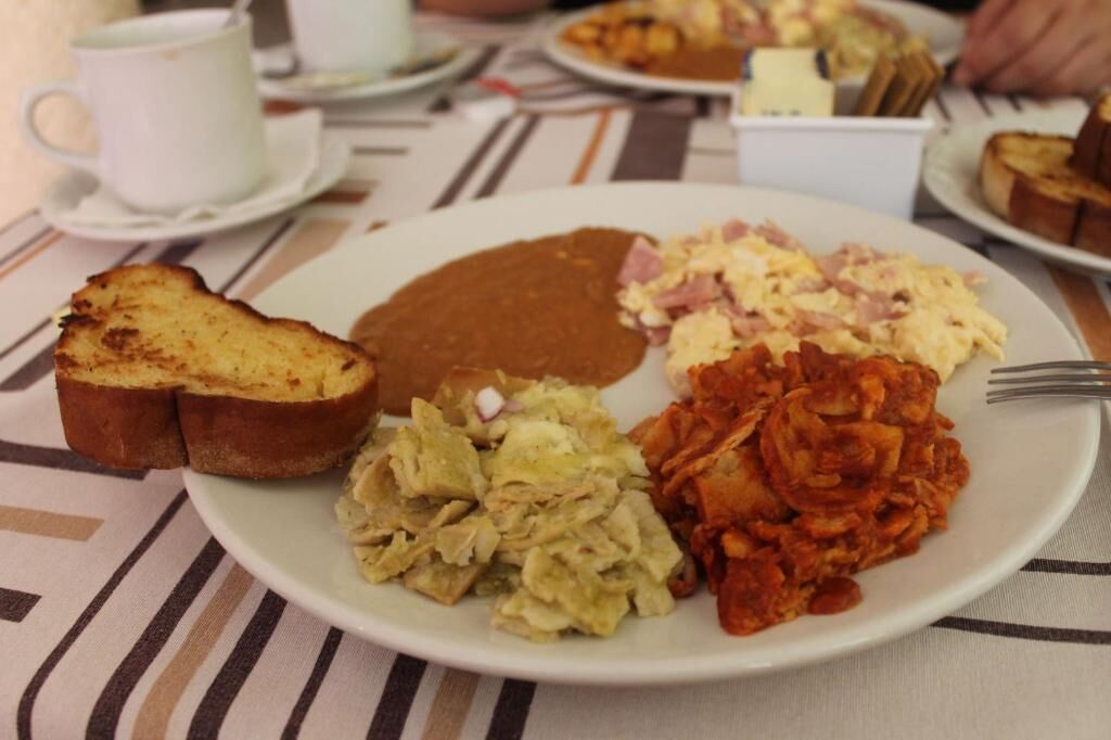 A plate with toast, scrambled eggs, beans, and a brown sauce.