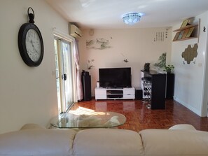 Relax in this stylish living room with a large wall-mounted clock, flat-screen TV, and comfortable sofa set.