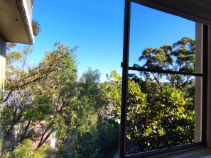 Enjoy a serene view of the lush outdoor area through the window, surrounded by trees and shrubs.