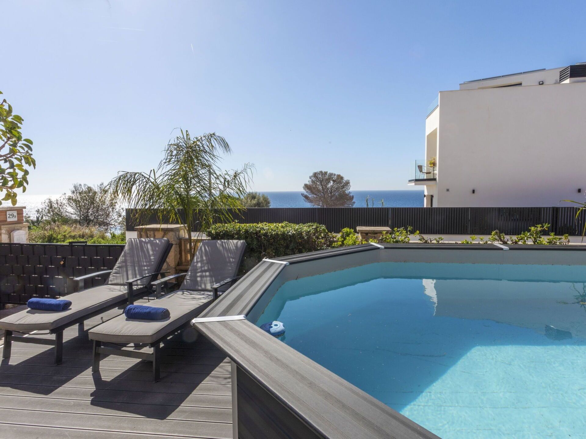 Una piscina con sillones de descanso y vistas al mar.