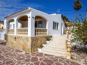 Situated in a sunny location, this Mediterranean-style building features a balcony with a balustrade and stone steps leading to the entrance.