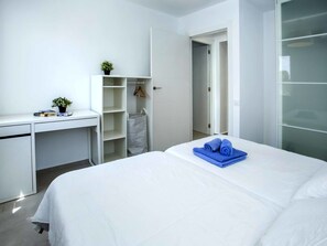Relax in a clean and minimalist space with a comfortable bed, desk, and closet.