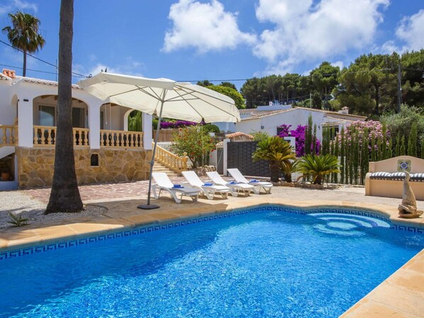 Relax by the serene pool surrounded by lush greenery and comfortable lounge chairs.