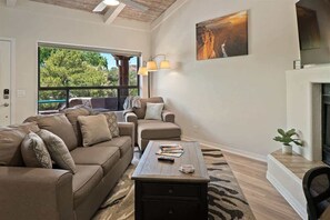 Uma sala de estar com sofá, poltrona, mesa de centro e um quadro na parede.