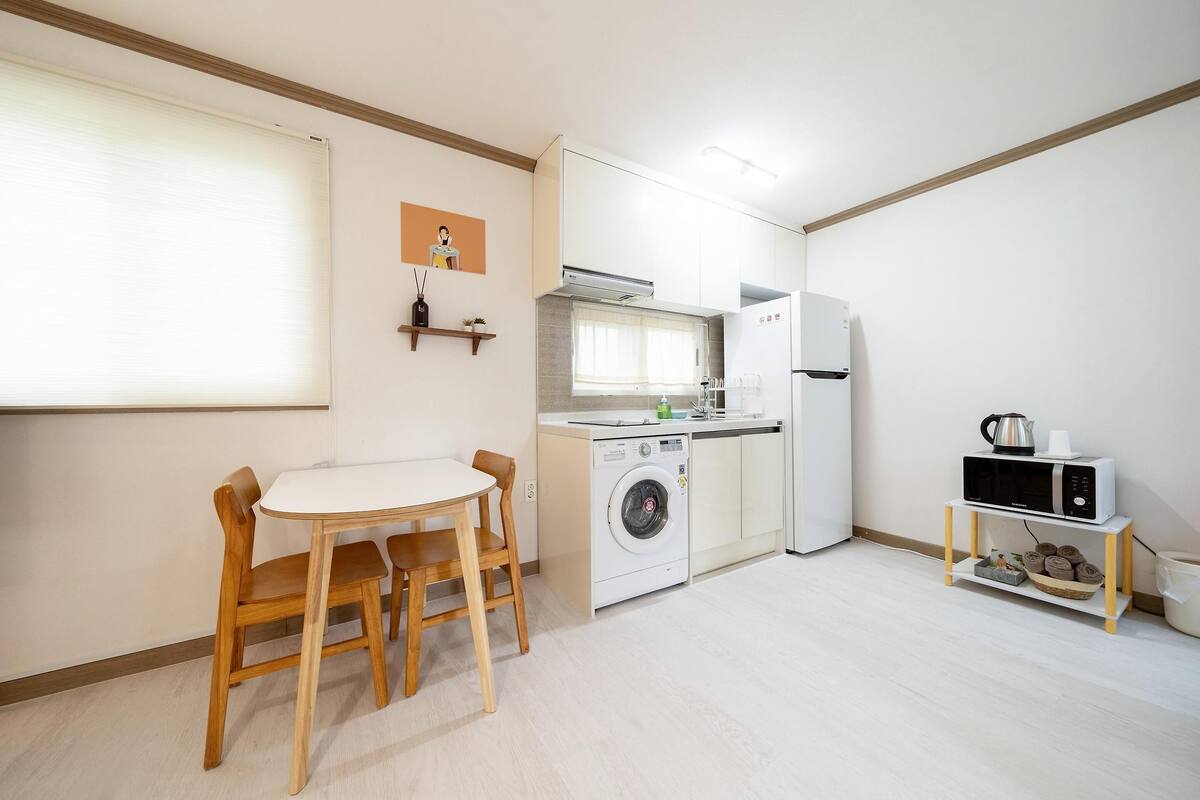 A compact kitchen with a washing machine, microwave, and refrigerator.