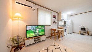 A modern apartment with a flat-screen TV, a dining area, a kitchen, and a living space. - Jeju Joyhouse (Seogwipo)
