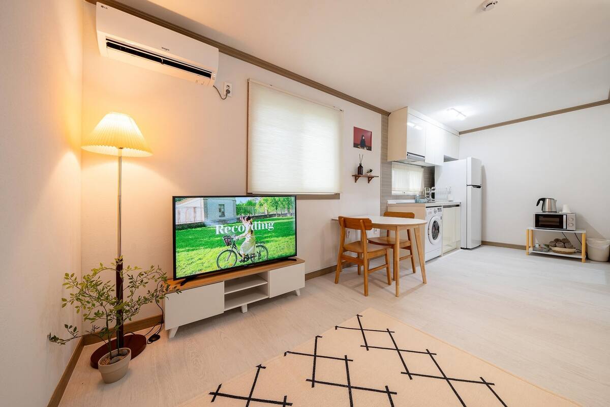 A modern apartment with a flat-screen TV, a dining area, a kitchen, and a living space.