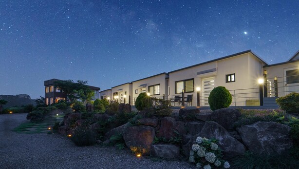 A modern two-story house with a well-maintained garden and a clear night sky. - Jeju Joyhouse (Seogwipo)