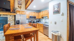 A kitchen with wooden cabinets, a microwave, stove, and a dining table with chairs. - Northwoods F3 - Chill`inn Slopeside (Davis)
