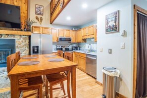 A kitchen with wooden cabinets, a microwave, stove, and a dining table with chairs.
