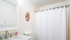 A bathroom with a white toilet, a sink with a marble countertop, and a shower curtain. - Northwoods F3 - Chill`inn Slopeside (Davis)