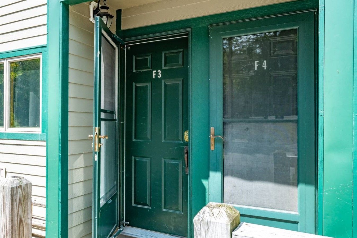 A green door with a number F3, a brass door handle, and a glass panel with the number F4.