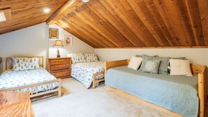 A cozy attic bedroom with two wooden beds, a dresser, and a small table. - Northwoods F3 - Chill`inn Slopeside (Davis)