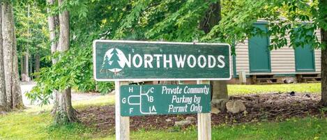 A sign indicating NORTHWOODS as a private community with parking by permit only.