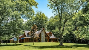 A log cabin with a stone chimney, surrounded by a well-maintained lawn and dense trees. - Back Country Cabin - Stunning, Secluded Property (Davis)