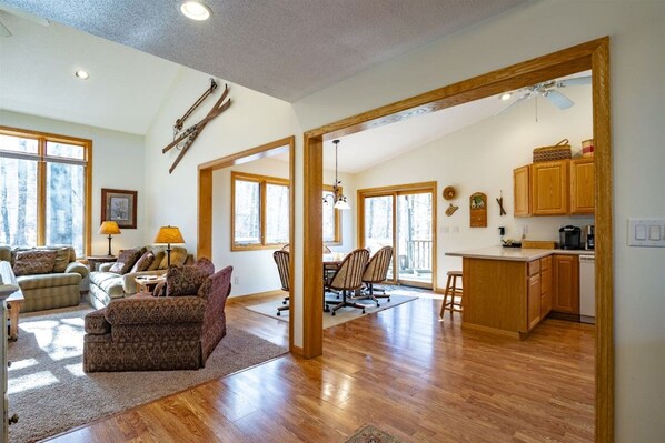 A spacious living area with a wooden floor, a dining table, and a kitchen area with wooden cabinets and a countertop.
